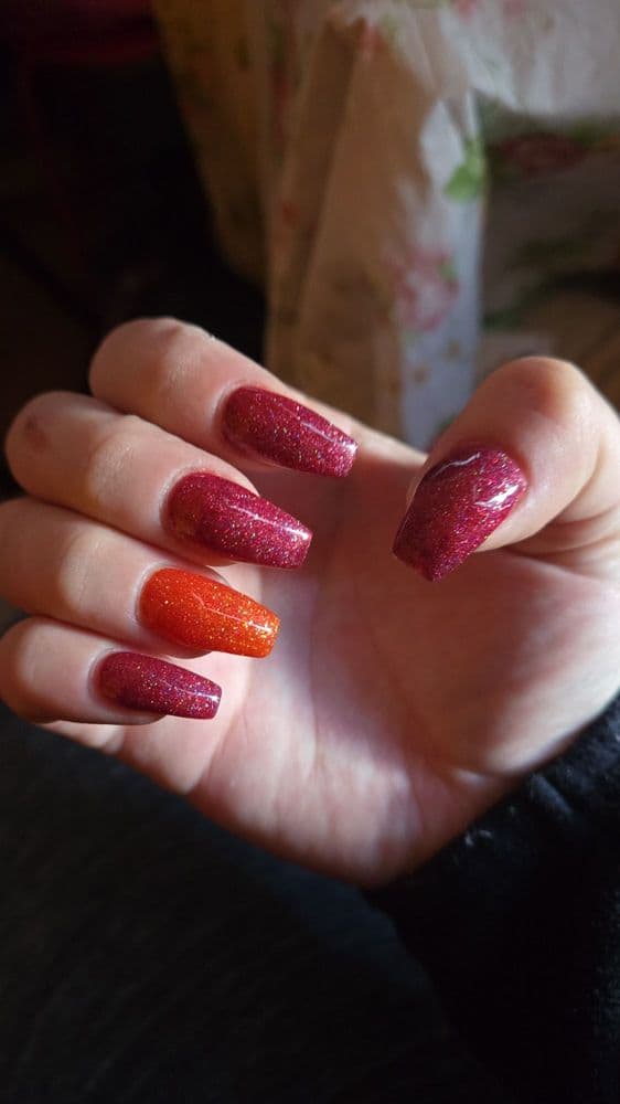 Long coffin nails with red and burgundy holographic glitter gel and orange accent nail by Nails by Ken