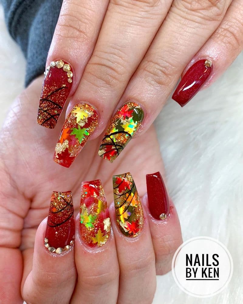 Long coffin nails with deep red and fall leaf nail art design by Nails by Ken