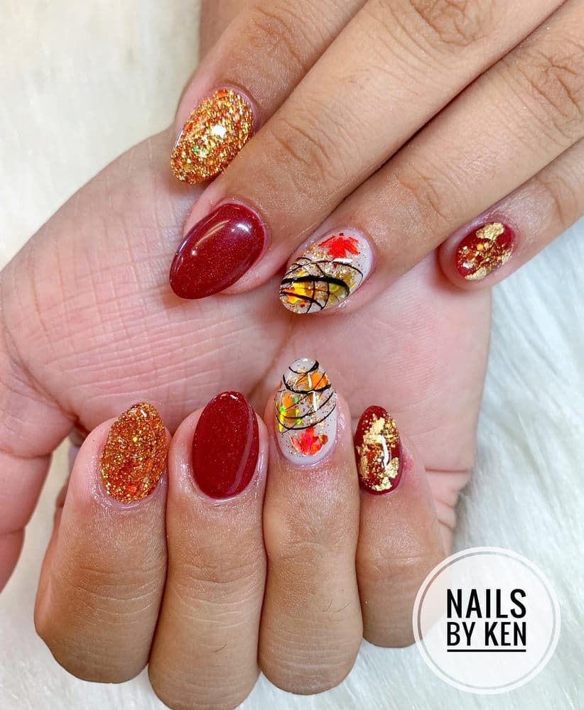 Short oval nails with fall autumn leaf art, red glitter and gold foil by Nails by Ken