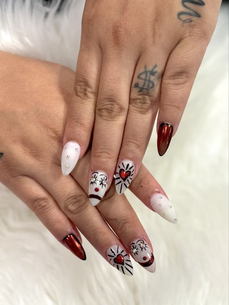 Stiletto nails with red chrome tips, white base with heart and smiley face nail art and rhinestones by Nails by Ken