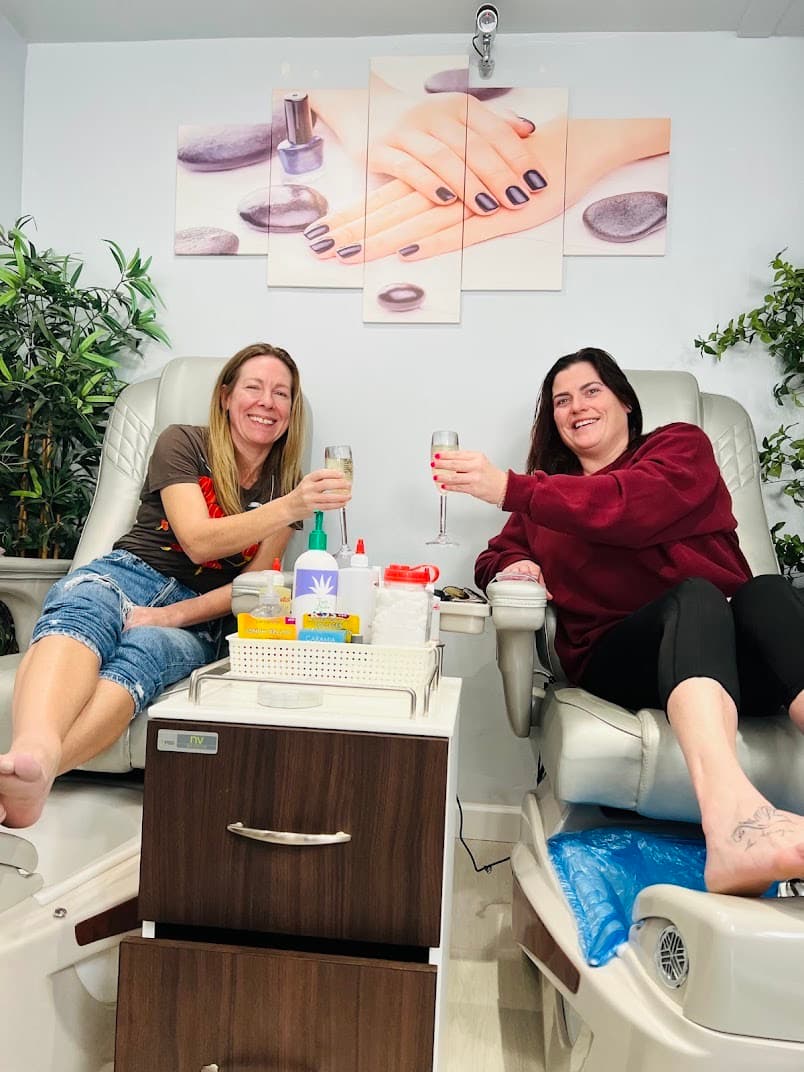 Two clients toasting with drinks in pedicure massage chairs at Nails by Ken, El Cerrito CA